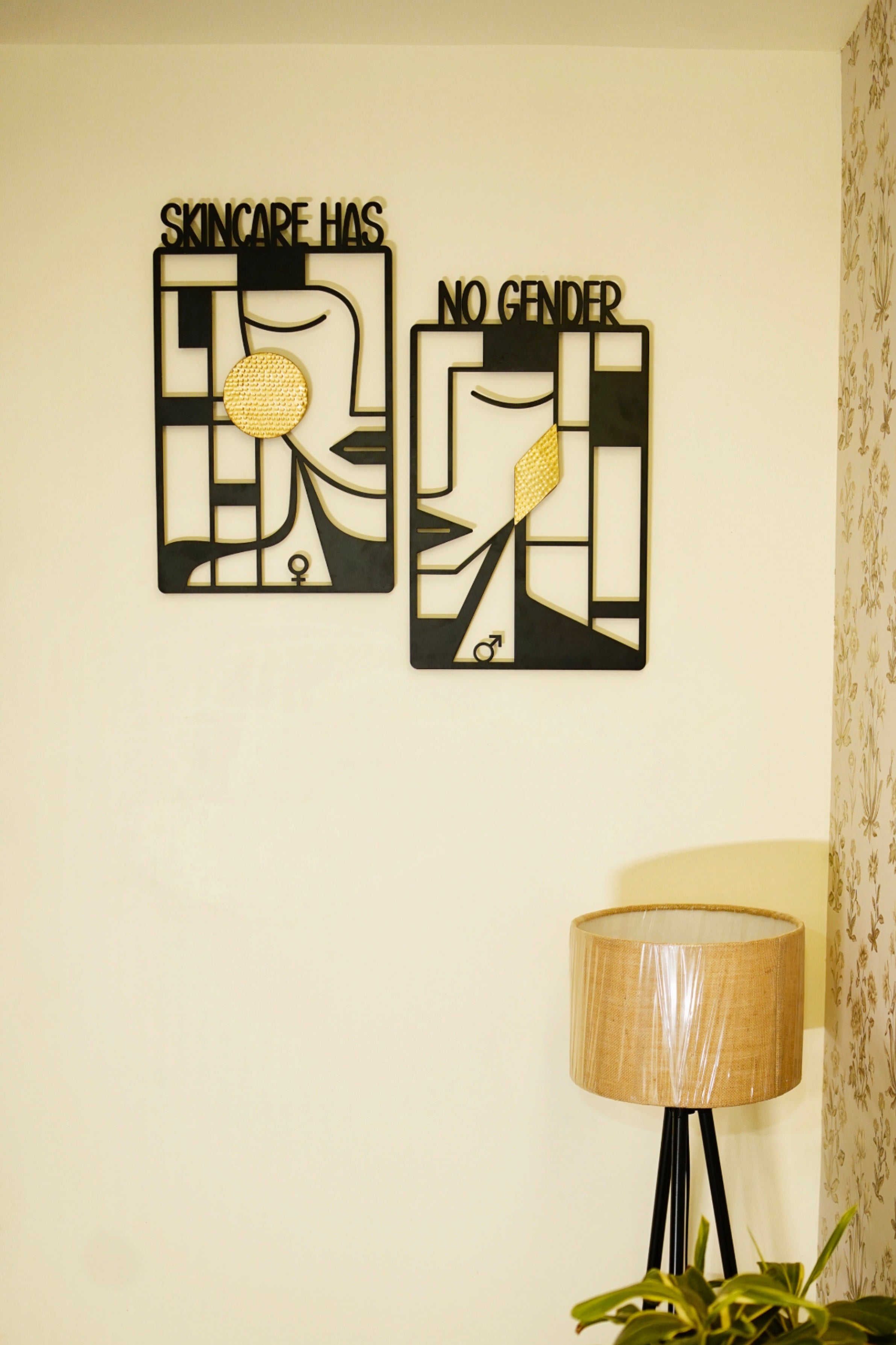 Decorative wall art with text on a light-colored wall, next to a lamp and plant.